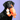 Black dog holding an orange plush crab toy against a purple background